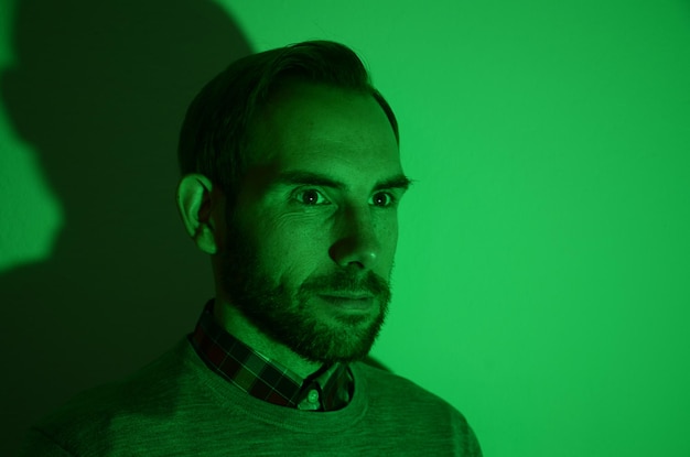 Close-up of man looking away against green wall