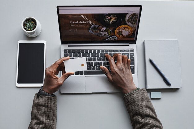 Close-up of man paying for online order with credit card he ordering food on laptop