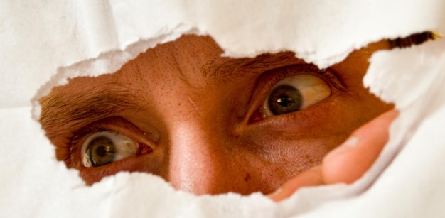 Photo close-up of man peeking through paper