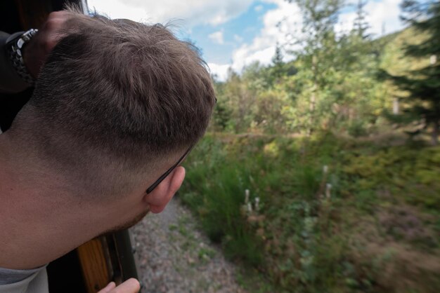 Foto close-up di un uomo che sbircia attraverso la finestra del treno