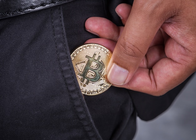 close up man pick bitcoin in to pocket