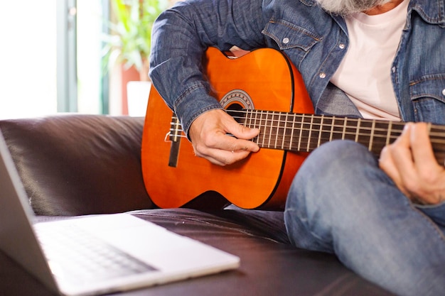 Foto close-up di un uomo che suona la chitarra acustica online