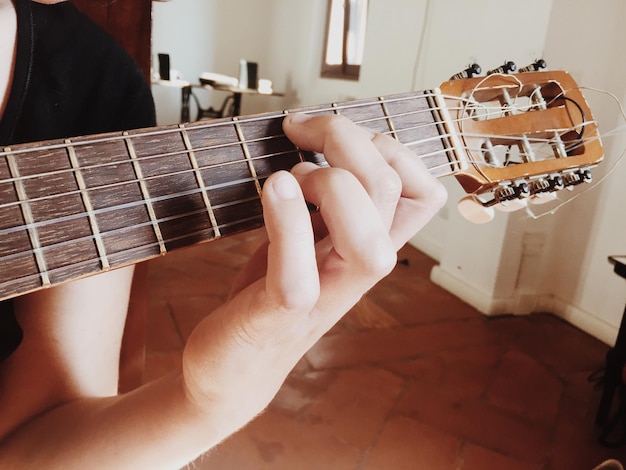 Foto close-up di un uomo che suona la chitarra a casa