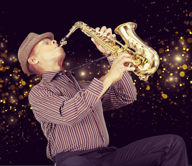 Close-up man playing on saxophone on dark background