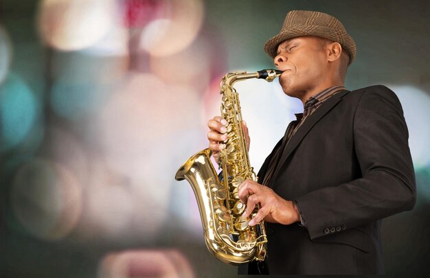 Close-up man playing on saxophone on dark background