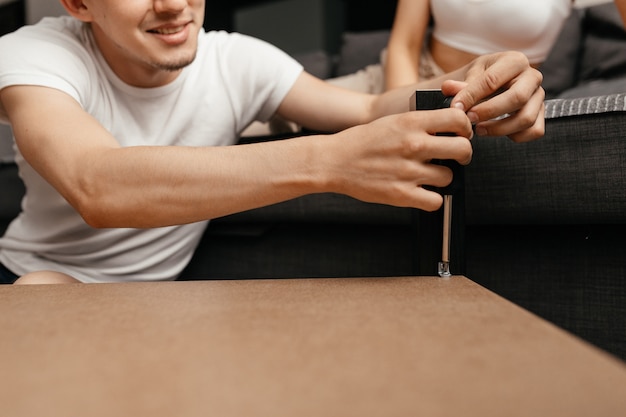 Close up on man repaing a table in his living room with a screwdriver