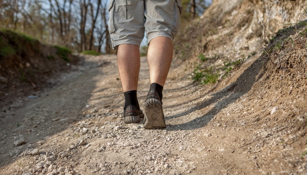 Chiuda in su dei piedi dell'uomo sulla strada forestale