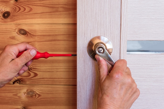 Close-up Of Man's Hand Installing Door Lock At Home.