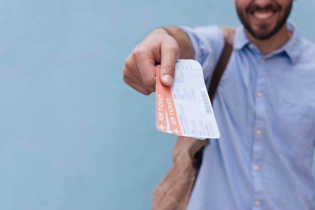 Photo close-up of man's hand showing air ticket on blue background