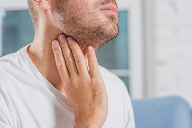 Close-up of a man's hand touching his throat