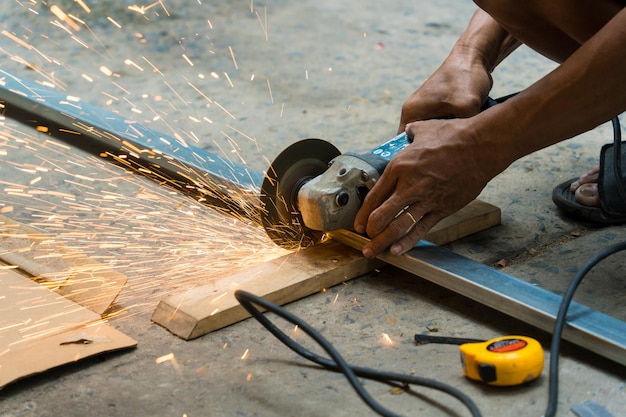 Photo close-up of man's hand using iron cutter to fastening the iron canopy frame with spark