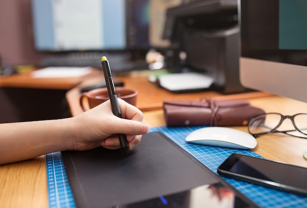 Close-up of a man's hand with a pen stylus drawing on a graphic tablet