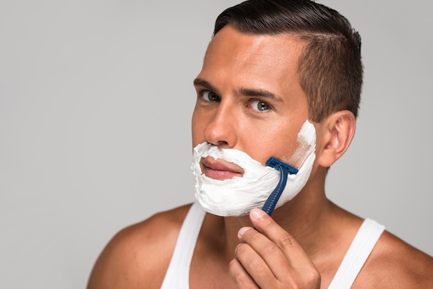 Photo close-up man shaving with razor