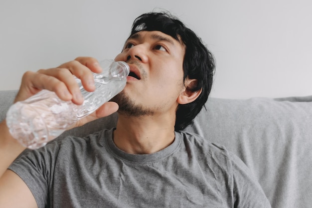 ソファに座って水のボトルを飲んでいる男のクローズアップ