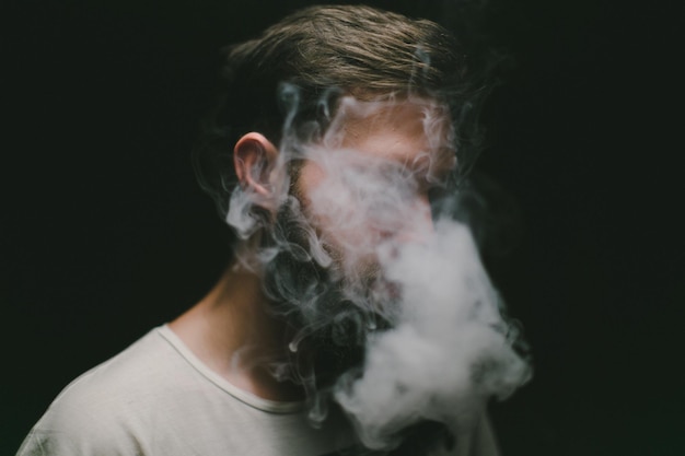 close-up of man smoking against black background