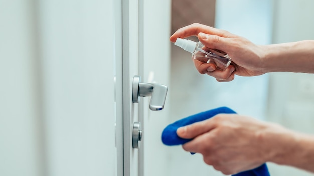 Close up man spraying antiseptic spray on the door handle