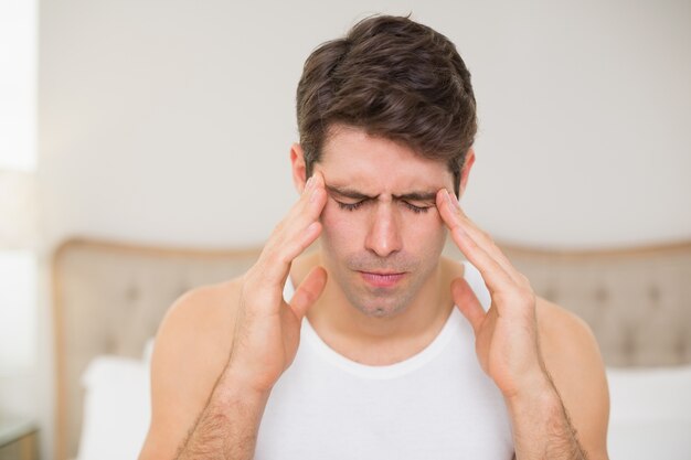 Close up of man suffering from headache in bed