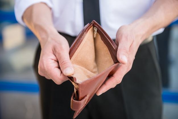 Close-up of man in suit holding empty purse.