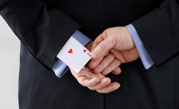 Photo close up man suit holds ace card behind his back