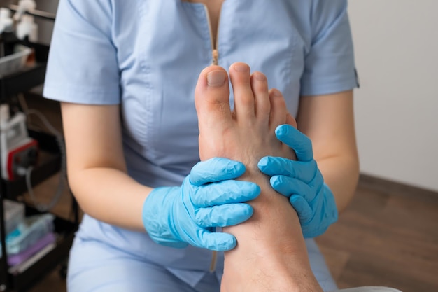 Foto da vicino un uomo si sottopone a una sessione di massaggio dei piedi da parte di un massaggiatore professionista alla clinica