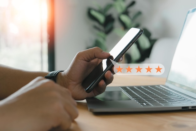 Close up A man uses a smartphone with a popup fivestar icon for feedback reviews and satisfaction with customer service and conducts a business satisfaction survey