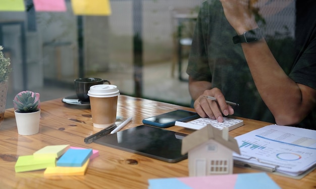 Photo close up man using calculator and laptop for do math finance on wooden desk in office and business working background, tax, accounting, statistics and analytic research concept