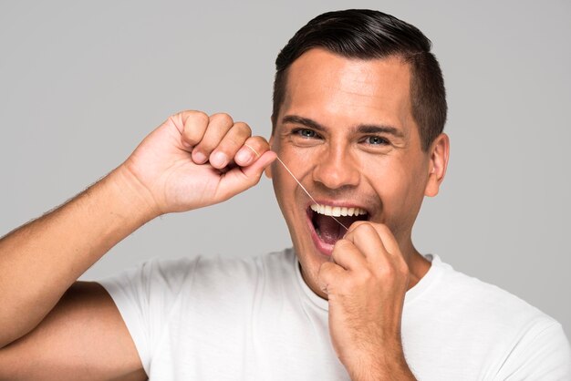 Close-up man using dental floss