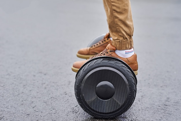 Photo close up of man using hoverboard on asphalt road. feet on electrical scooter outdoor