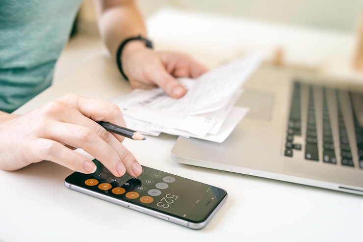 Photo close-up of man using laptop and calculator on table
