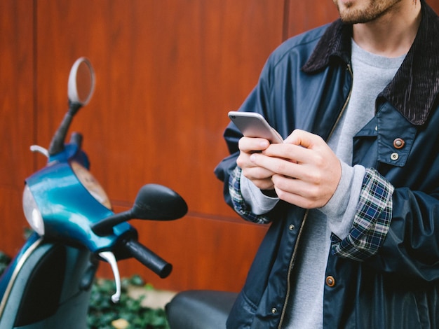 スクーターで携帯電話を使っている男性のクローズアップ