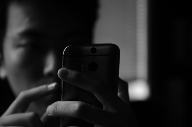 Photo close-up of man using phone in darkroom