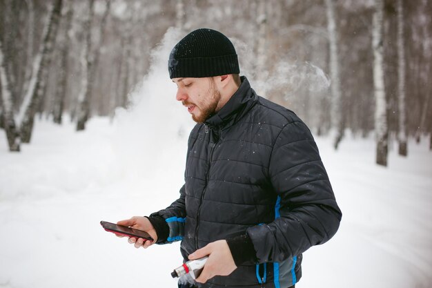 Photo close-up of man using phone while smoking on snow covered field