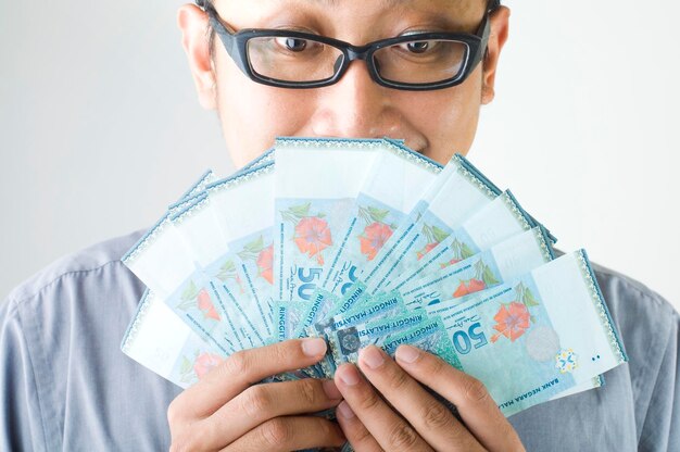 Close-up of man wearing eyeglasses holding fanned out currency