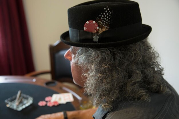 Foto close-up di un uomo che indossa un cappello con una fichetta da gioco e una piuma