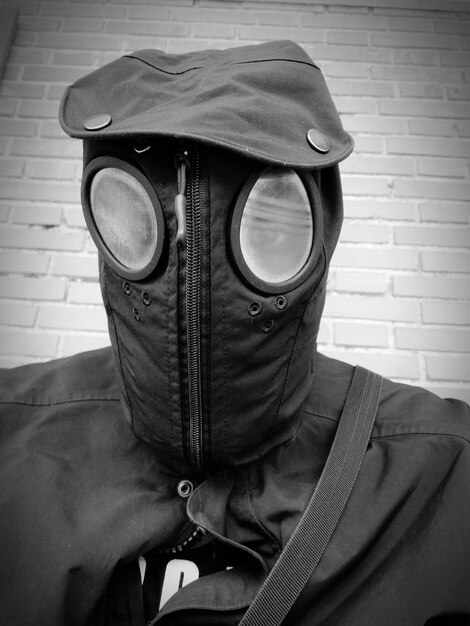 Photo close-up of man wearing mask against brick wall