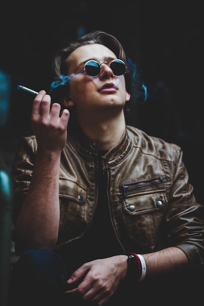 close-up of man wearing sunglasses smoking cigar