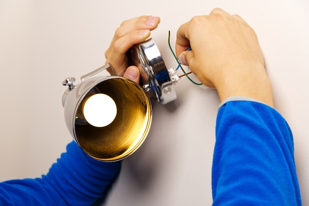 Close up on man wiring lamp wires onto wall