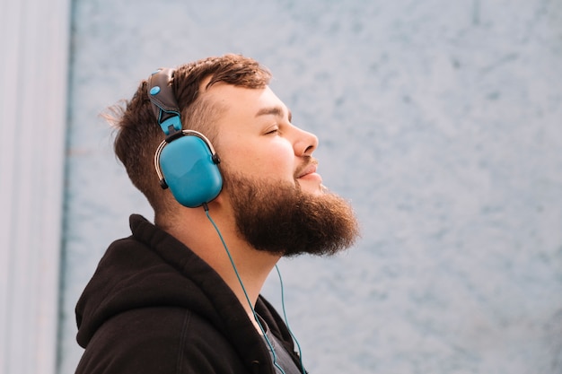 Foto primo piano di un uomo con la musica d'ascolto della barba sulle cuffie