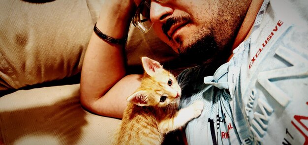 Foto close-up di un uomo con un gatto che si rilassa sul divano