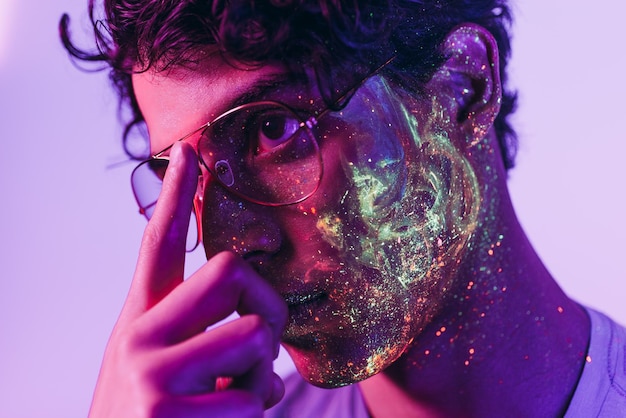 Close-up of man with multi colored face paint wearing eyeglasses
