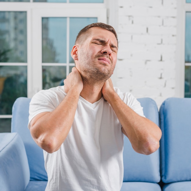 Photo close-up of a man with pain in his neck at home