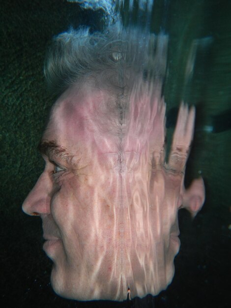 Foto close-up di un uomo con il riflesso sull'acqua in piscina