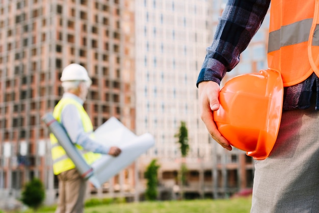 Photo close-up man with safety vest holding helmet