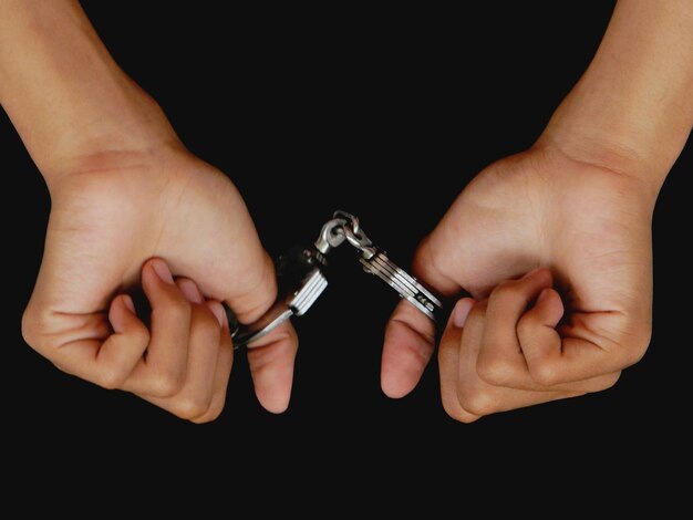 Близкий снимок человека с небольшими наручниками на черном фоне