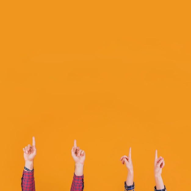 close-up of man and woman pointing his finger upward against an orange background