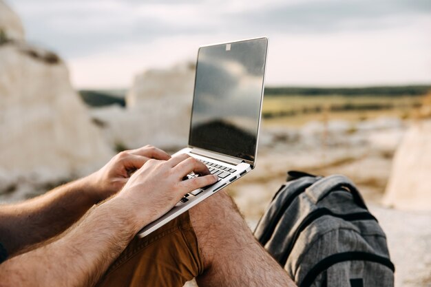 Close-up of a man working on the laptop outdoors. Freelance concept.