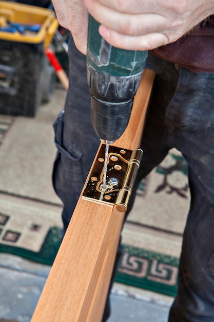 Close-up of man working on wooden plank with equipment at workshop