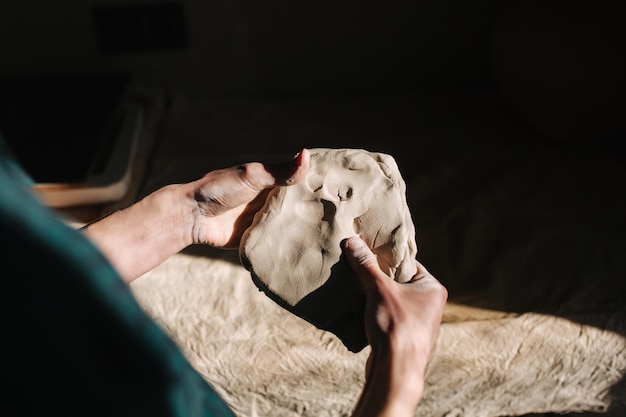 Close up of man works with clay Male potter kneads and moistens the clay before work toned