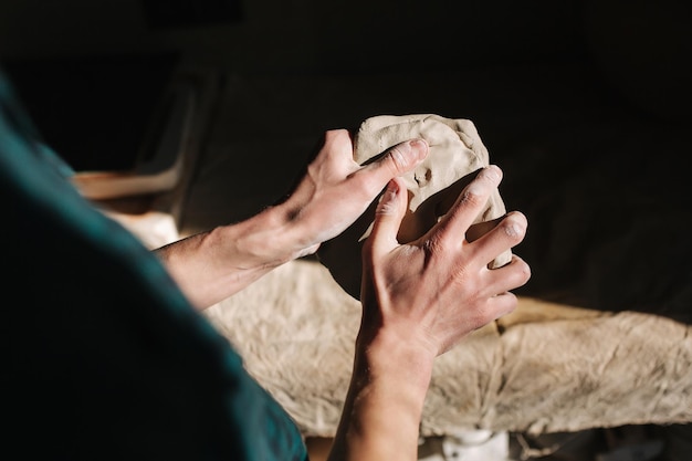 Close up of man works with clay Male potter kneads and moistens the clay before work toned