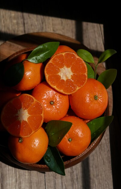 close up of Mandarins with leafs in a wooden bowl